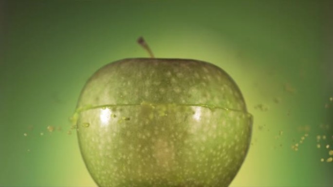 半个青苹果掉落并溅在绿色背景上。食物悬浮概念。慢动作