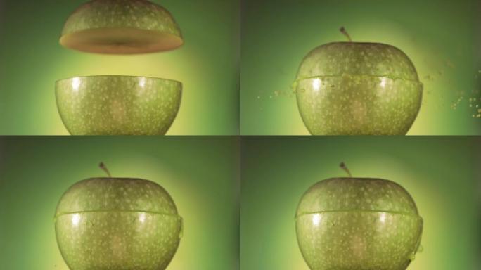 半个青苹果掉落并溅在绿色背景上。食物悬浮概念。慢动作