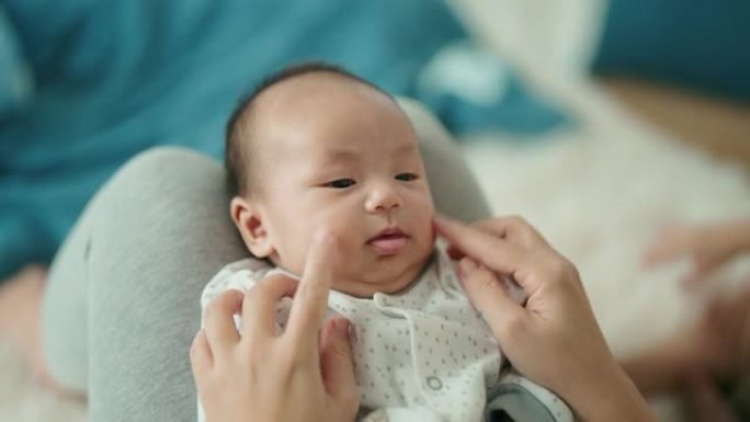 微笑的亚洲妈妈和她可爱的新生男婴玩耍