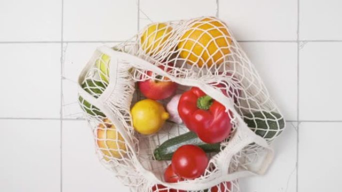 有机收获的水果和蔬菜从市场可重复使用的袋子。男人从绳子包里拿苹果。健康饮食食品。顶视图