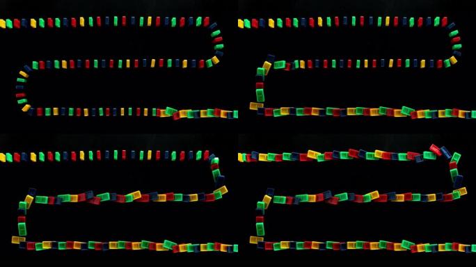 SLO MO LD一排彩色多米诺骨牌落在黑色表面上