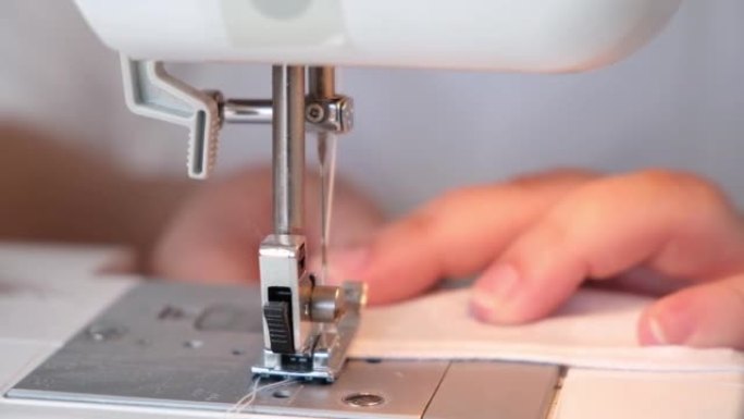 一个女人正在缝制窗帘的下摆，枕套的边缘，衣服，缝纫机上的床单。
