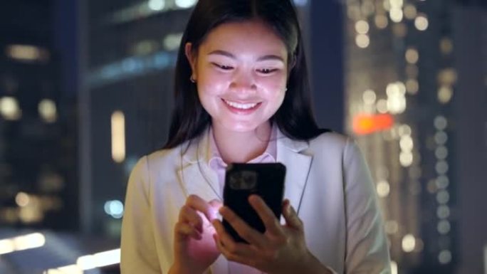 亚洲妇女在城市的夜晚使用智能手机。