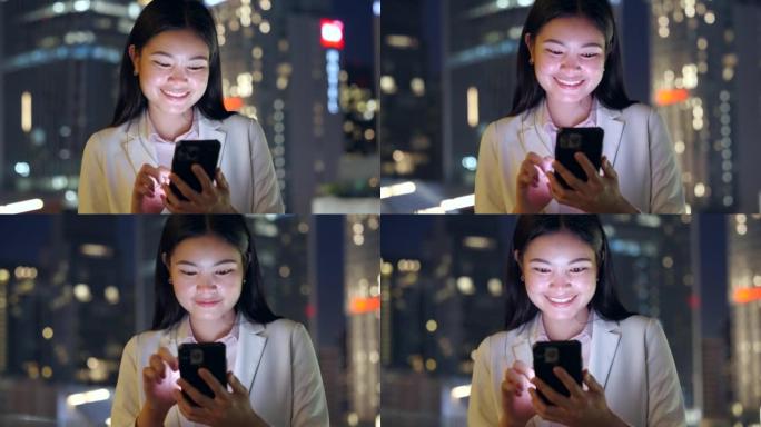 亚洲妇女在城市的夜晚使用智能手机。