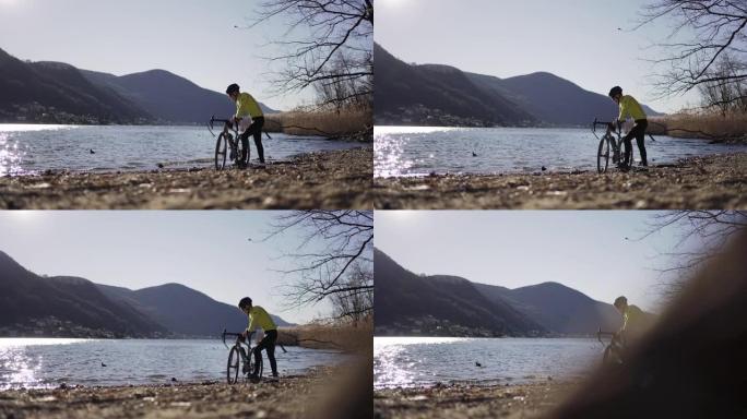 骑自行车的人停下来，在阳光明媚的日子里看着湖景