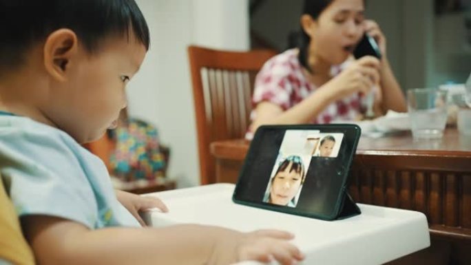 蹒跚学步的孩子在家在数字平板电脑上进行视频通话。