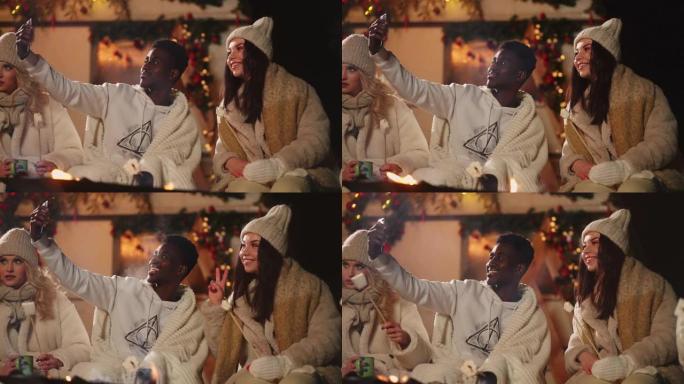 黑人男子在圣诞晚会上与朋友通过电话自拍，在篝火旁微笑着