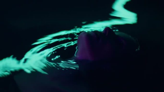优雅的女人漂浮在霓虹色的水上。奢华护发比喻