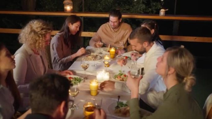 无忧无虑的多种族男女朋友，在餐厅阳台上享用晚餐