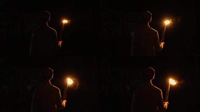 一个穆斯林男孩拿着火把在夜里行走，只是为了照亮道路