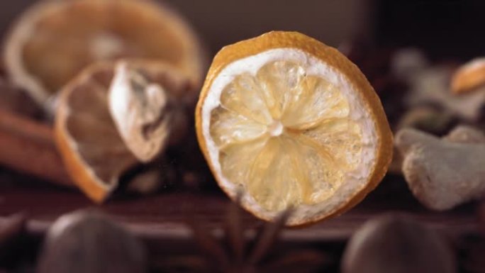 柠檬片和生姜落在木头上的香料中。慢动作