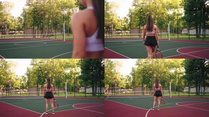 年轻迷人的女网球运动员正在空荡荡的球场上，女运动员形象的后视图