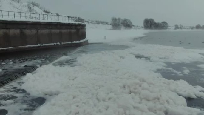 无人机视频。下水道排入河中，瀑布。冬天，水上泡沫