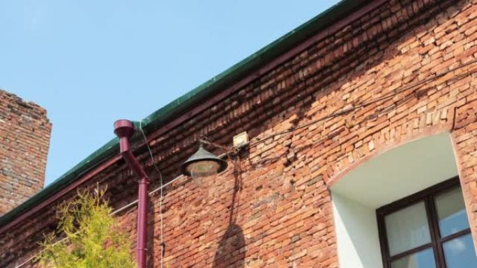 红色砖墙保护灯泡中的老式壁挂式路灯。户外