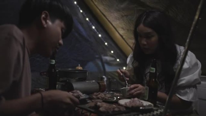 年轻夫妇一起坐在帐篷里吃食物