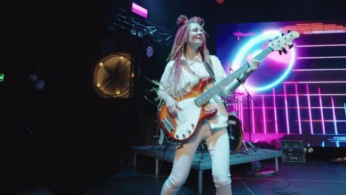 时尚女吉他手留辫子在舞台上嬉戏跳舞，摇滚音乐音乐会