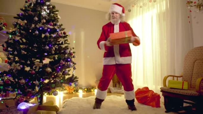 宽镜头快乐的圣诞老人在室内跳舞，看着相机。开朗积极的大胡子白人老人圣诞节父亲在客厅玩得开心。新年快乐