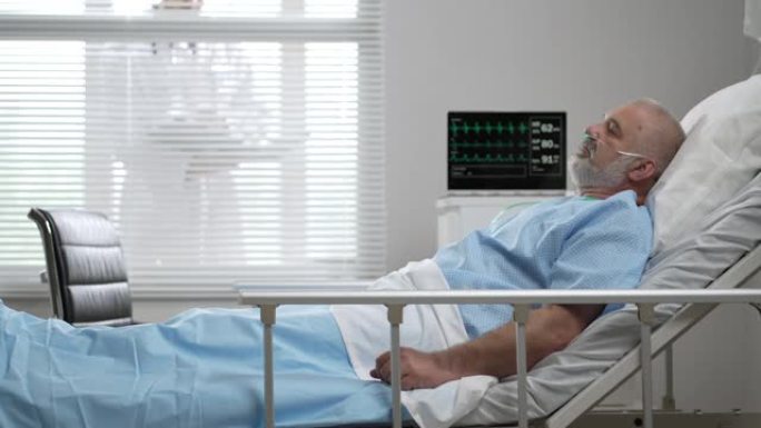在诊所里，一位老人，病人躺在与心电图机相连的床上，医生站在病房的窗户外面，看着指示器。