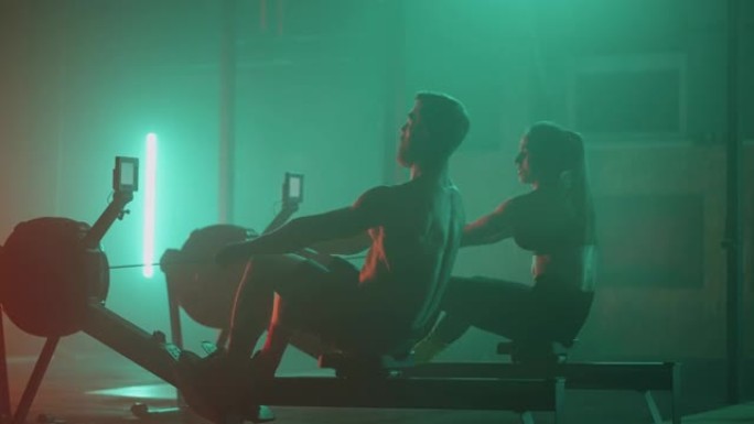 一男一女表演强壮的运动员在健身房用划船机慢动作进行锻炼