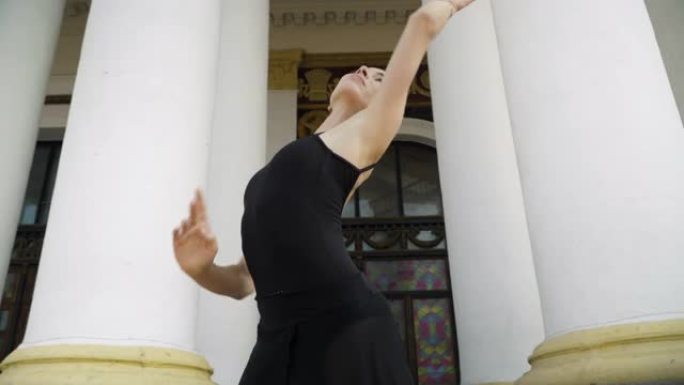 迷人的年轻高加索芭蕾舞演员在户外柱子上的城市楼梯上移动。自信苗条女人跳交际舞的肖像。舞蹈艺术和美的概