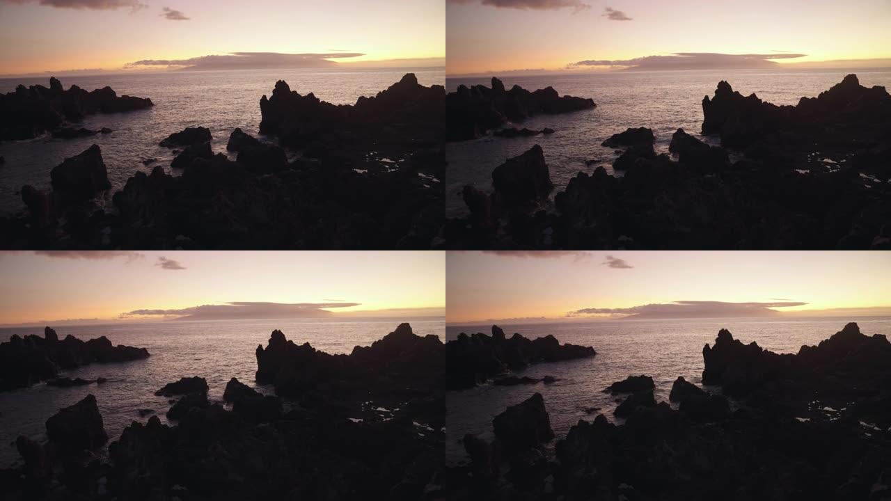 火山海岸线形成对比。黑色的岩石和夕阳在海里反射。