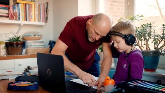 远程学习，男孩和爸爸看着电脑屏幕并做笔记