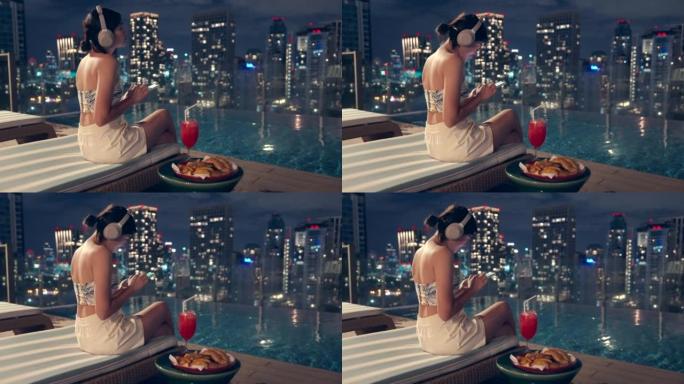 她在泰国曼谷城景高楼的游泳池区听音乐。