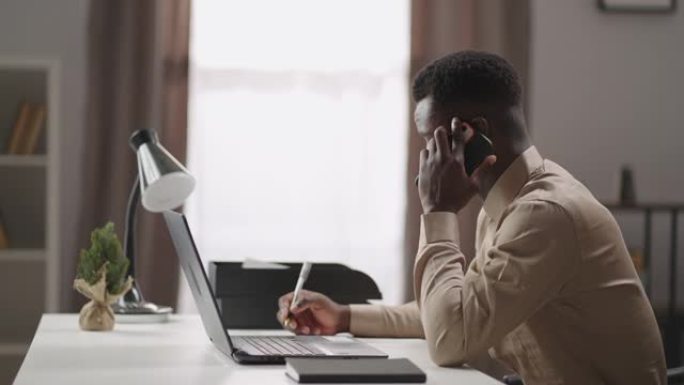 黑人正在用手机聊天，在家庭办公室远程工作，年轻的商人