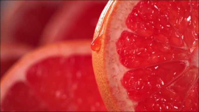 一滴葡萄柚汁从成熟多汁的葡萄柚片的表面流下。慢动作4K