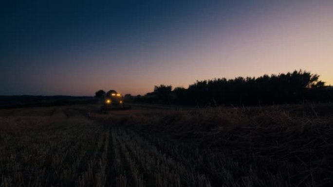 农民驾驶收割机在日落时分在田间收割小麦