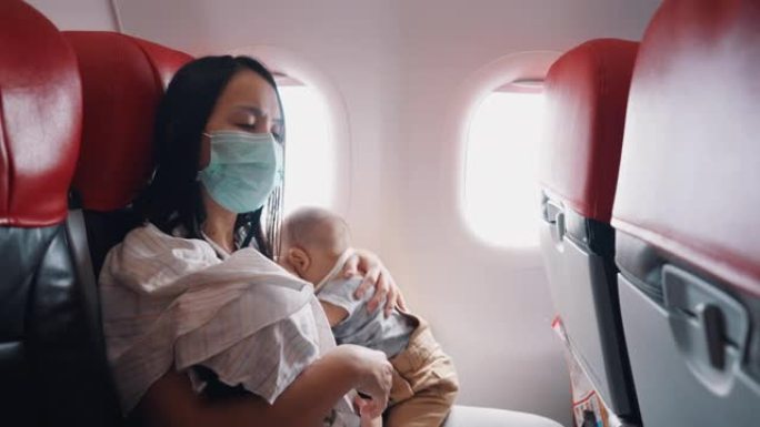 小男孩乘飞机旅行时睡在妈妈怀里