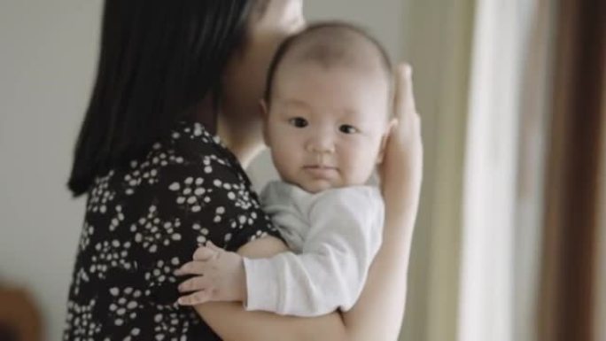 年轻的亚洲妈妈抱着她可爱的男婴