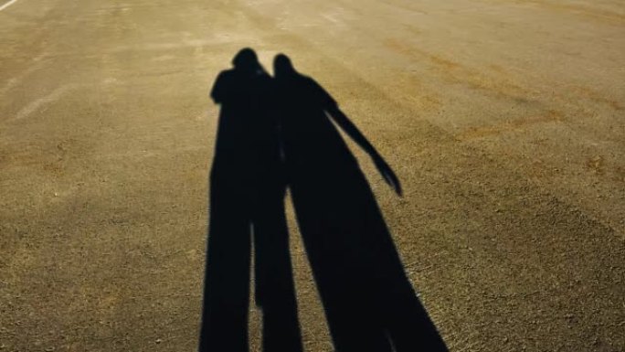 在路上行走的两个人的影子一男一女。细长轮廓