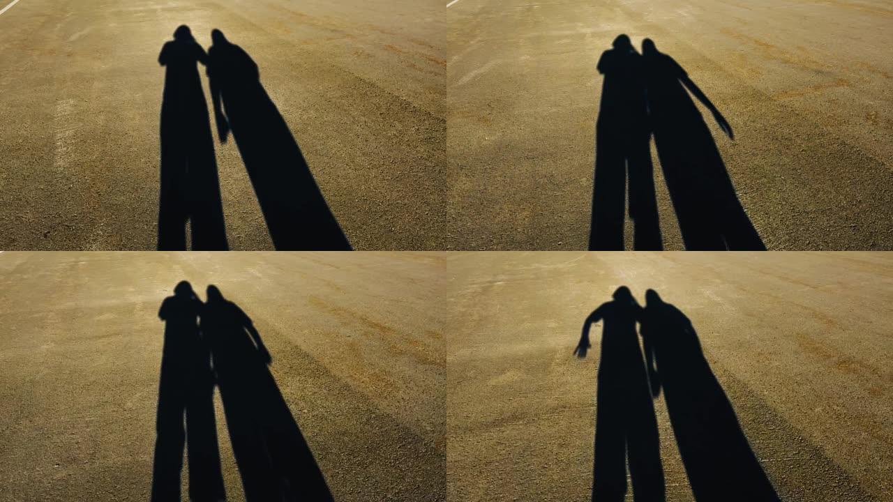 在路上行走的两个人的影子一男一女。细长轮廓