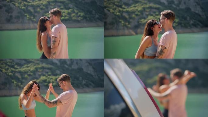 可爱的年轻夫妇站在美丽的绿松石湖边接吻