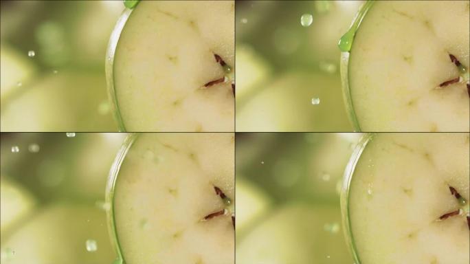 一滴绿色果汁从成熟多汁的绿色苹果片的表面流下。慢动作4K