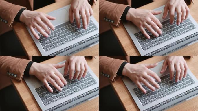 男性手放在现代笔记本电脑的键盘上，从顶部特写镜头，上班族正在发送信息