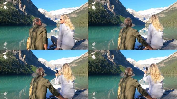夫妇在湖岸山上放松，拍照并看着