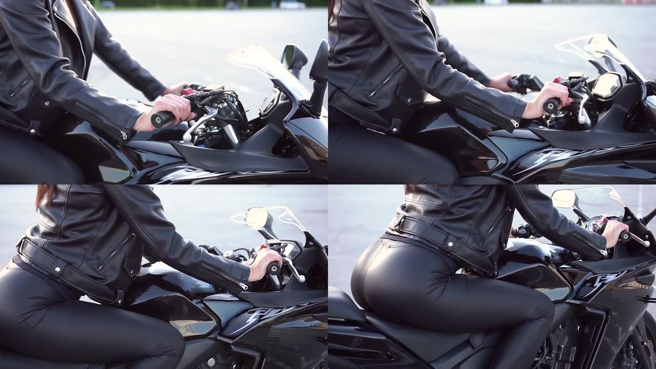 穿着时尚皮衣的年轻苗条女摩托车手坐在运动场上的黑色运动型摩托车上