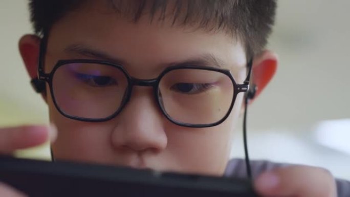 Closeup face Asian boy wearing glasses play game o