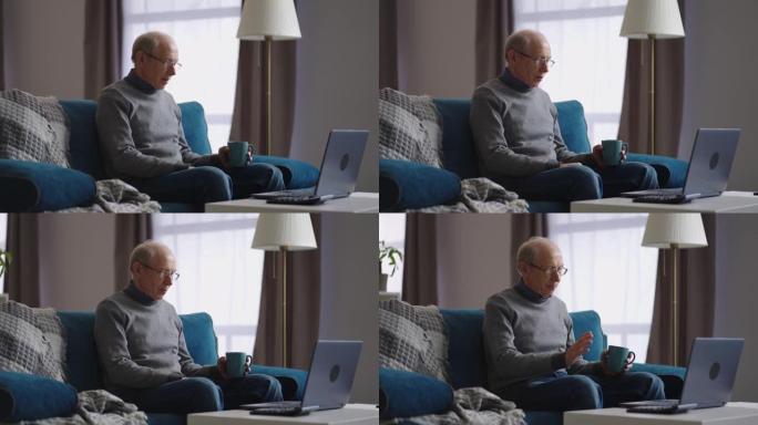 老人独自一人坐在家里，通过与朋友或家人的视频聊天进行交流，看着笔记本电脑的网络摄像头