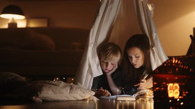 儿子和妈妈在冬夜躺在帐篷里读童话书中的神奇故事