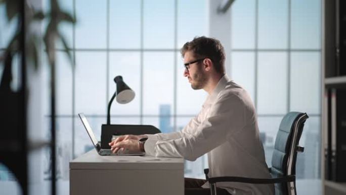 在他的大城市办公室里，有思想的成功商人在笔记本电脑上工作的肖像。数字企业家为电子商务战略做数据分析。