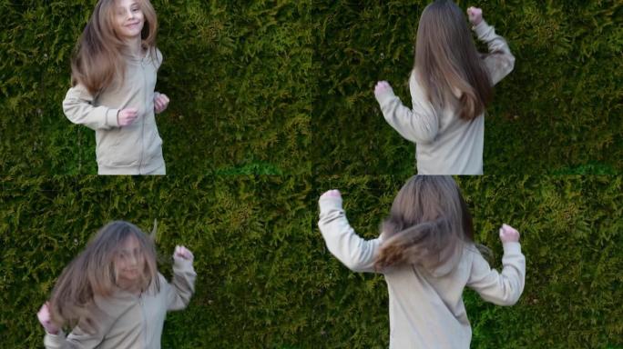 一个穿着米色西装的可爱女孩在户外跳舞的慢动作视频，快乐的孩子在花园里跳舞
