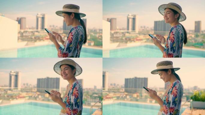 高层建筑上的亚洲女孩屋顶游泳池，并在手机中查看社交媒体。