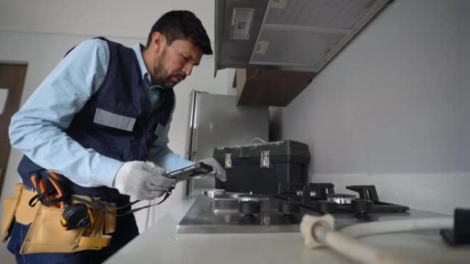 拉丁美洲的燃气技术员用机器检查家用炉灶上是否有燃气泄漏