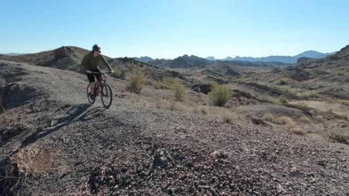 男性山地自行车手沿着崎岖的地形沙漠路径