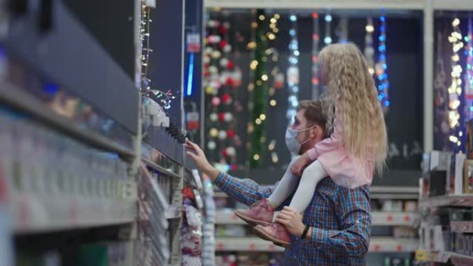 肩膀上的父女在超市为圣诞节选择圣诞花环