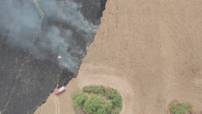 扑灭了农田大火。就在一片庄稼着火后。直升机的鸟瞰图。棕灰色的烟雾和红色的小火焰。消防员的团队合作。消