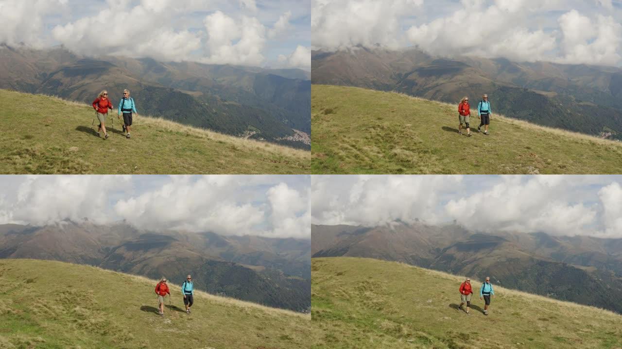 一对夫妇沿着草木山顶徒步旅行的空中无人机拍摄